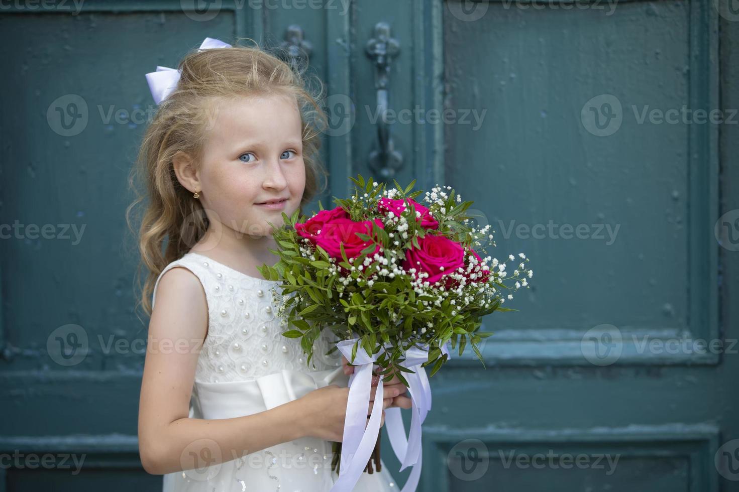 uma fofa pequeno menina é segurando uma ramalhete do flores mulheres dia. pequeno menina e flor. feliz criança em feriado com flores foto