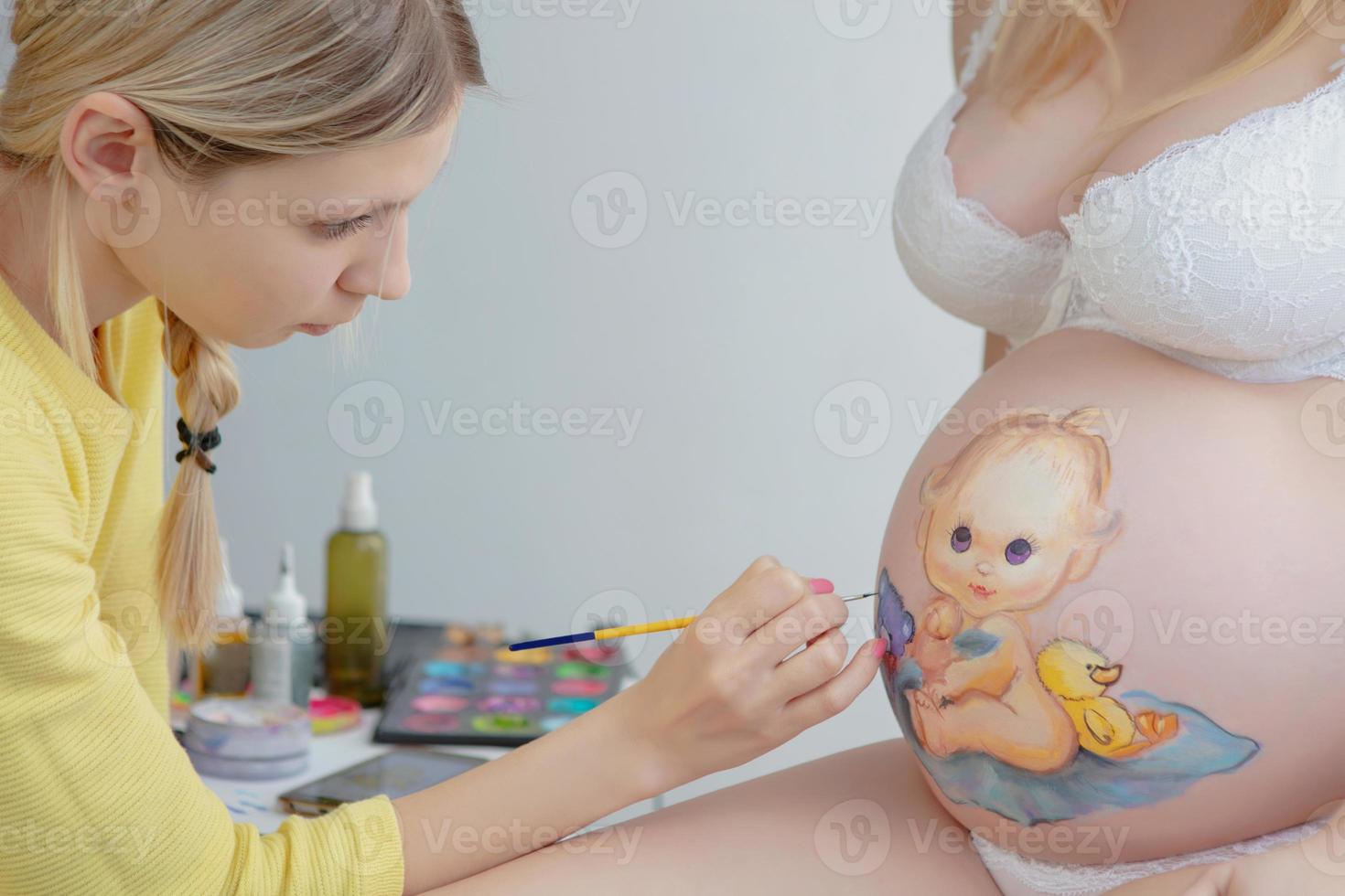 Maquiagem artista desenhar uma criança pequena em a barriga foto