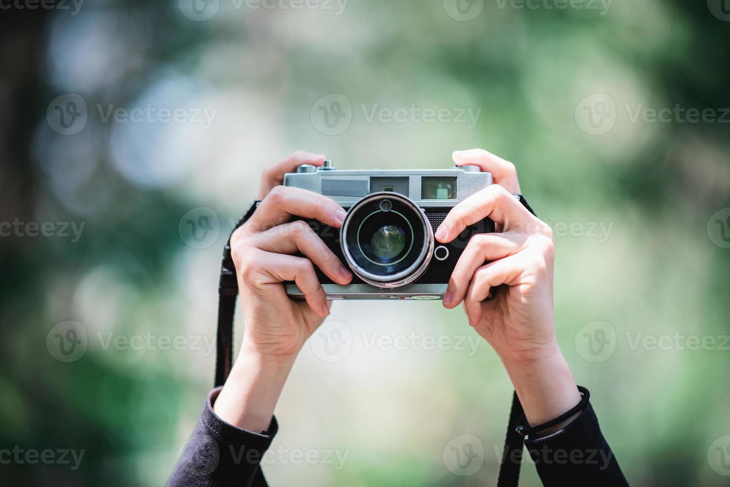 mãos do fêmea profissional fotógrafo leva instantâneos dentro floresta foto