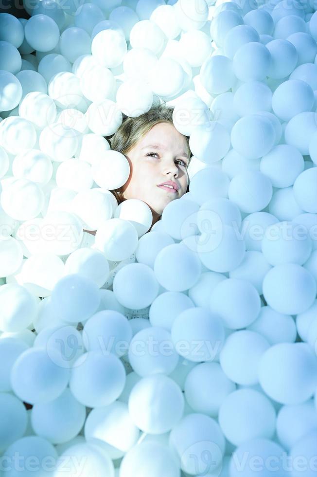 uma menina é jogando com branco bolas, uma crianças sala de jogos. foto