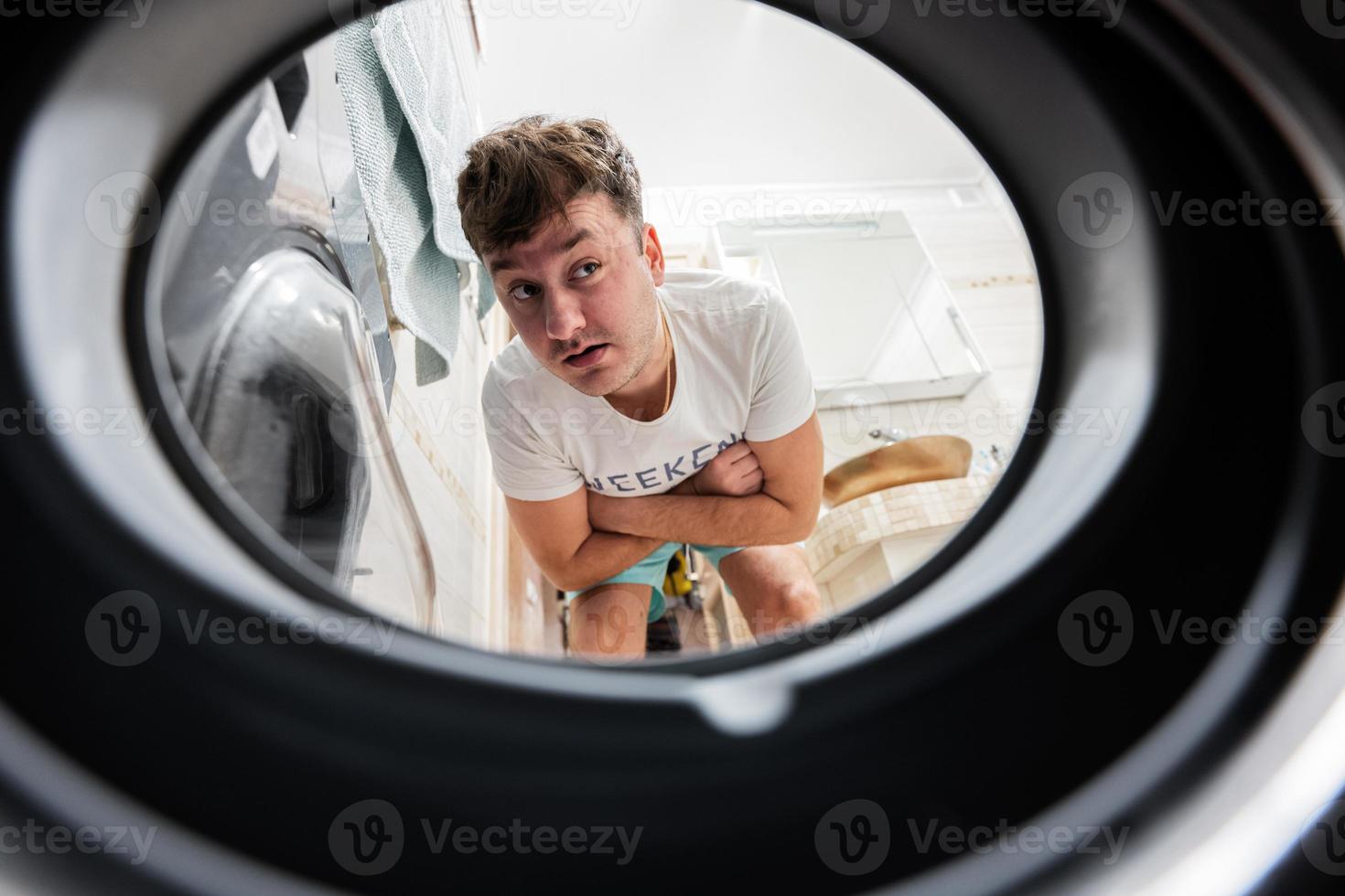 homem Visão a partir de lavando máquina dentro. masculino faz lavanderia diariamente rotina. espera para a lavando para terminar. foto