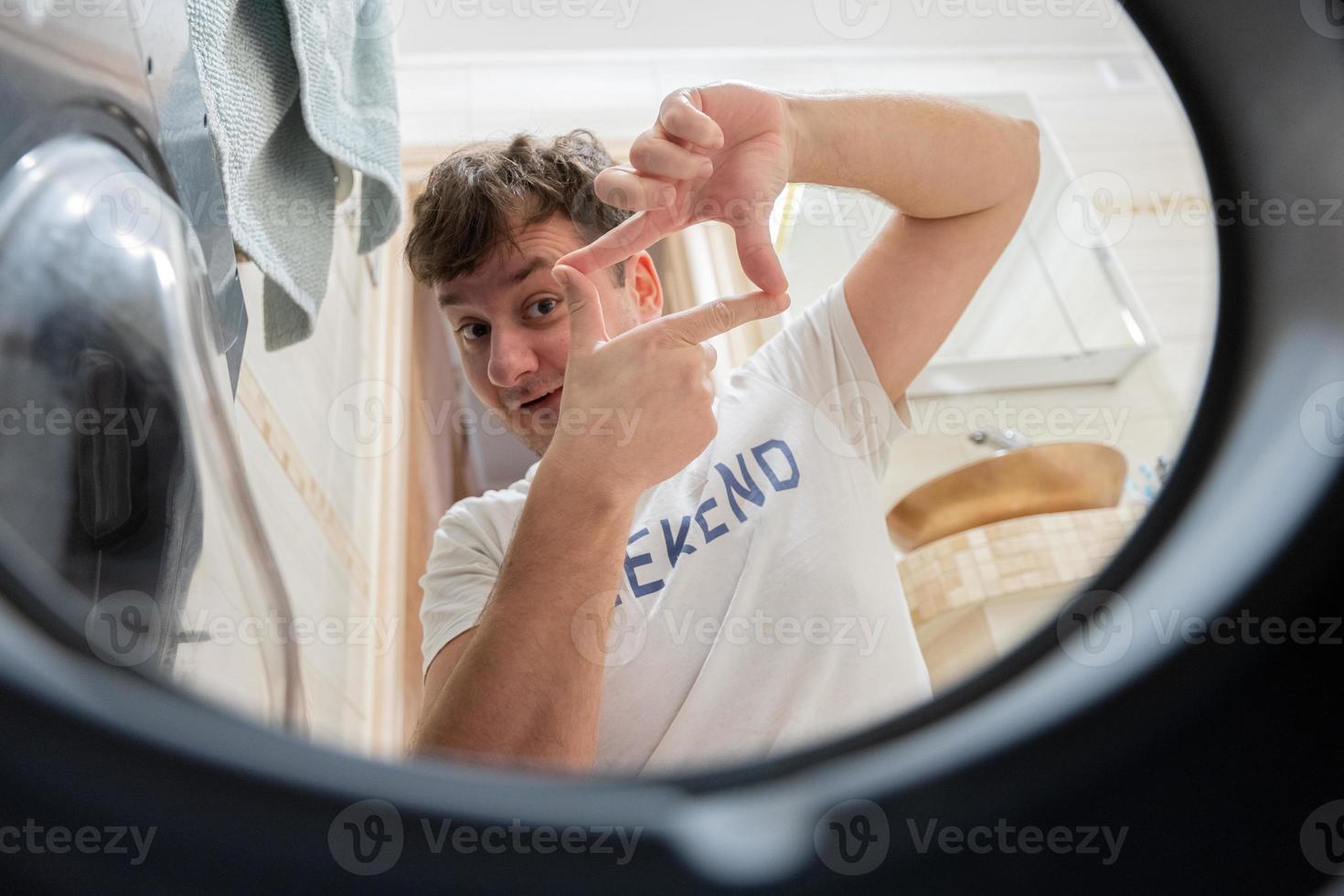 homem Visão a partir de lavando máquina dentro. masculino faz lavanderia diariamente rotina. fez uma foto quadro, Armação com dedos.