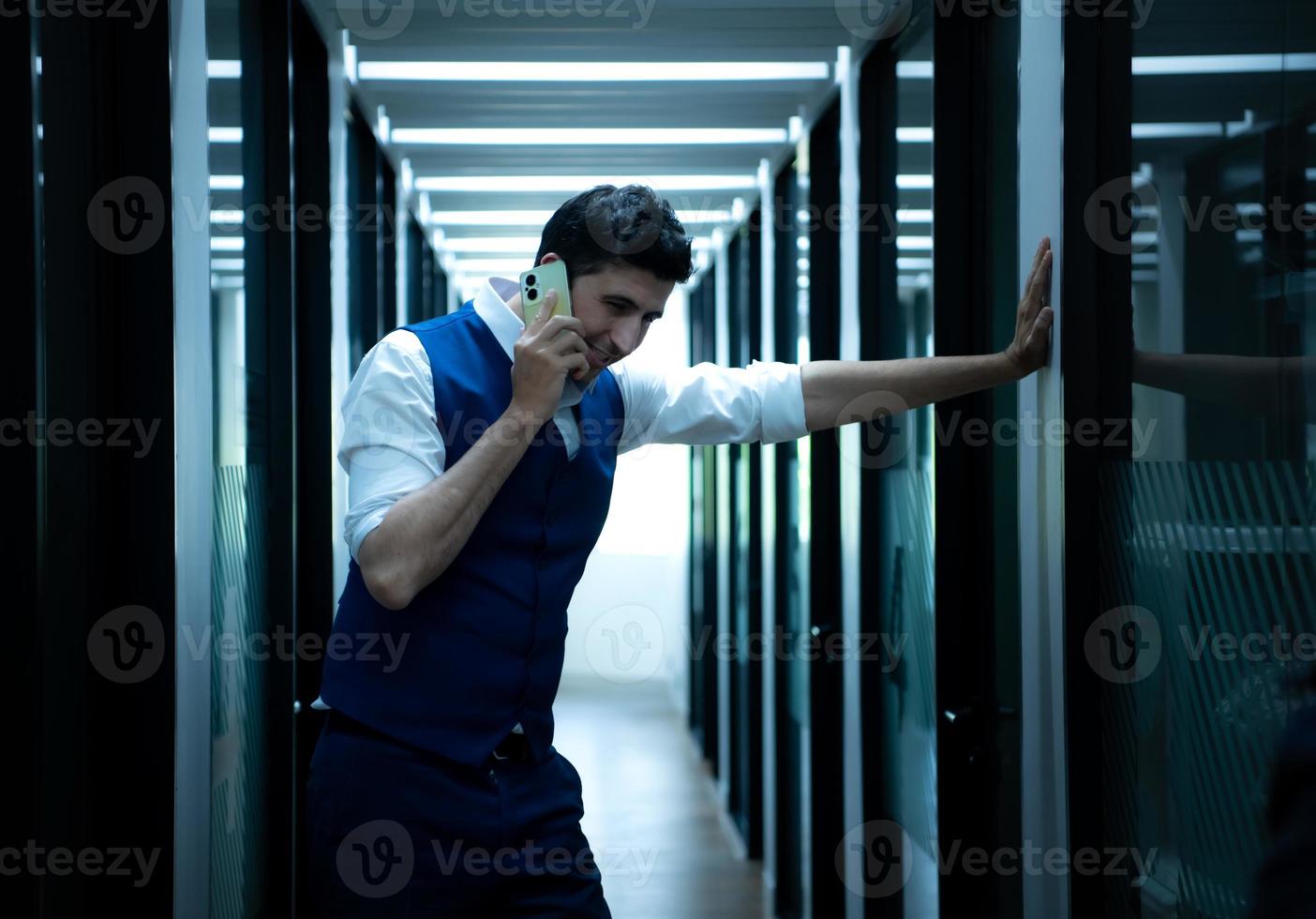 o negócio homem dentro a corredor do a conferência sala, falando para a assistente em a telefone para perguntar para alguns detalhes. foto