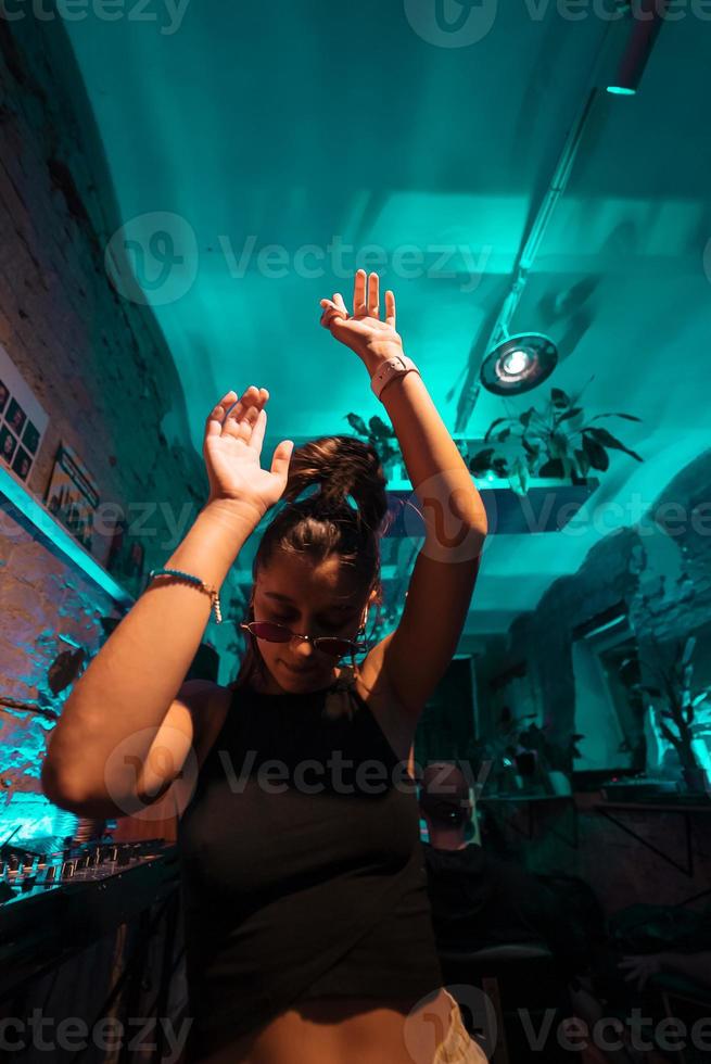 bela dj feminina dançando techno em um pequeno clube foto