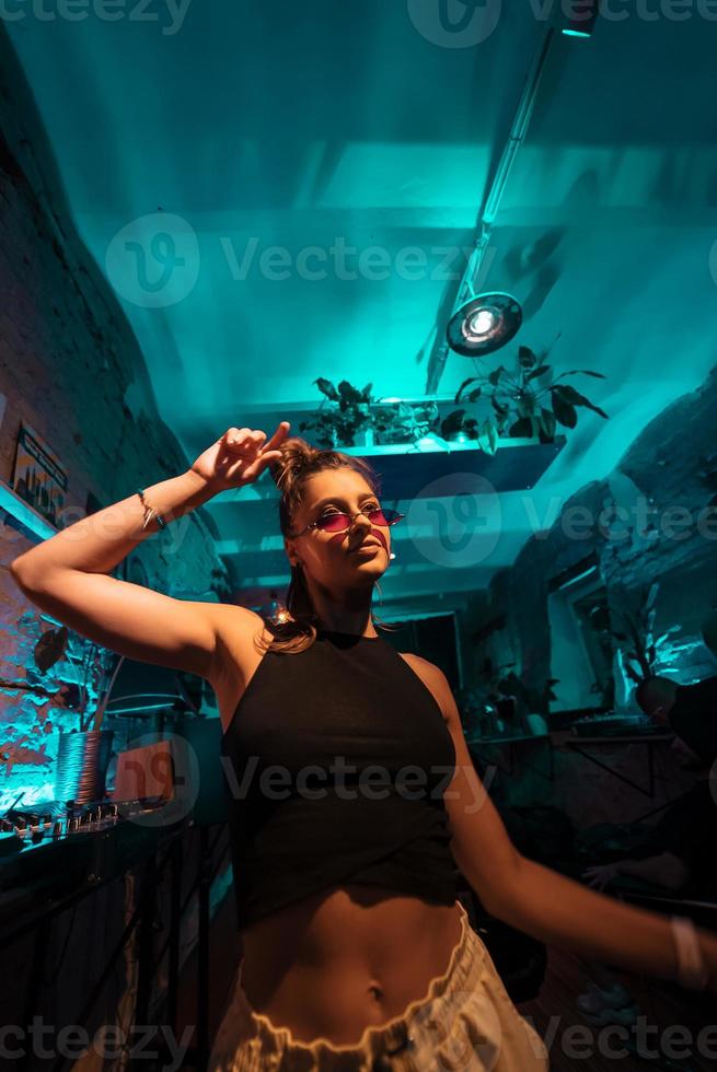 bela dj feminina dançando techno em um pequeno clube foto