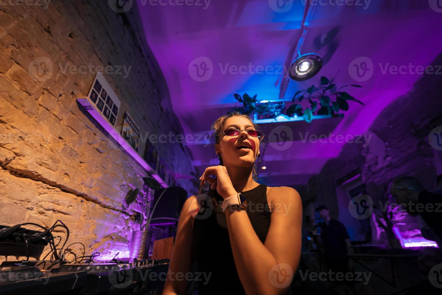 bela dj feminina dançando techno em um pequeno clube foto