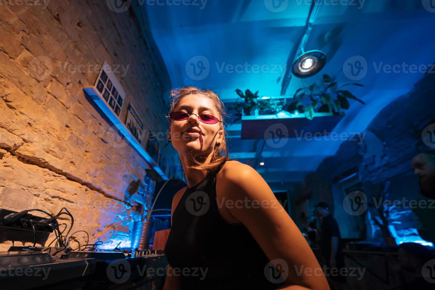 bela dj feminina dançando techno em um pequeno clube foto