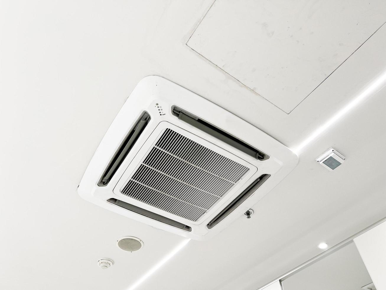 condicionador de ar tipo cassete montado no teto e luz de lâmpada moderna no teto branco. ar condicionado de duto para casa ou escritório foto