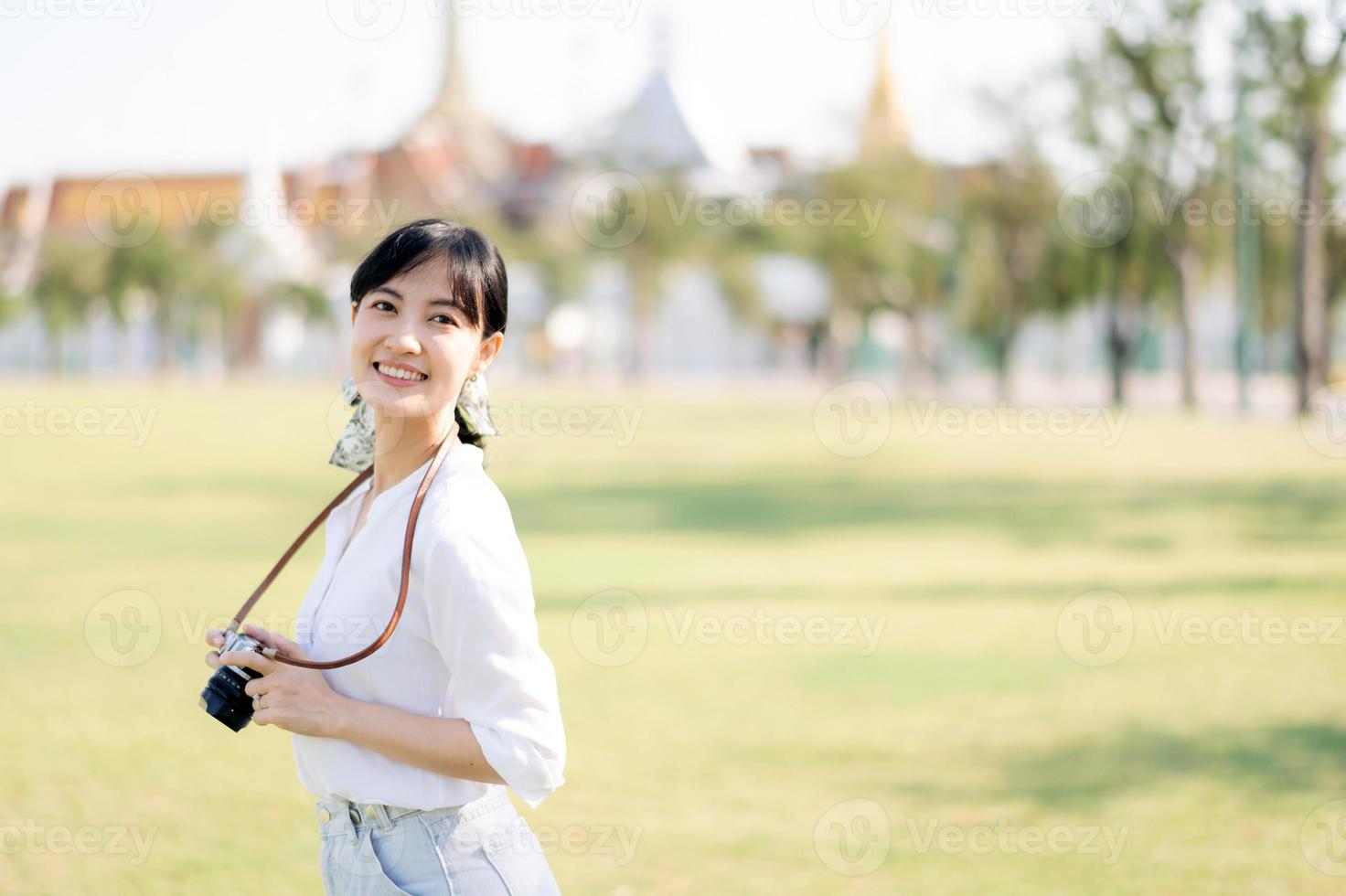 retrato do ásia mulher viajante usando Câmera. Ásia verão turismo período de férias conceito com a grande Palácio dentro uma fundo às Bangkok, Tailândia foto