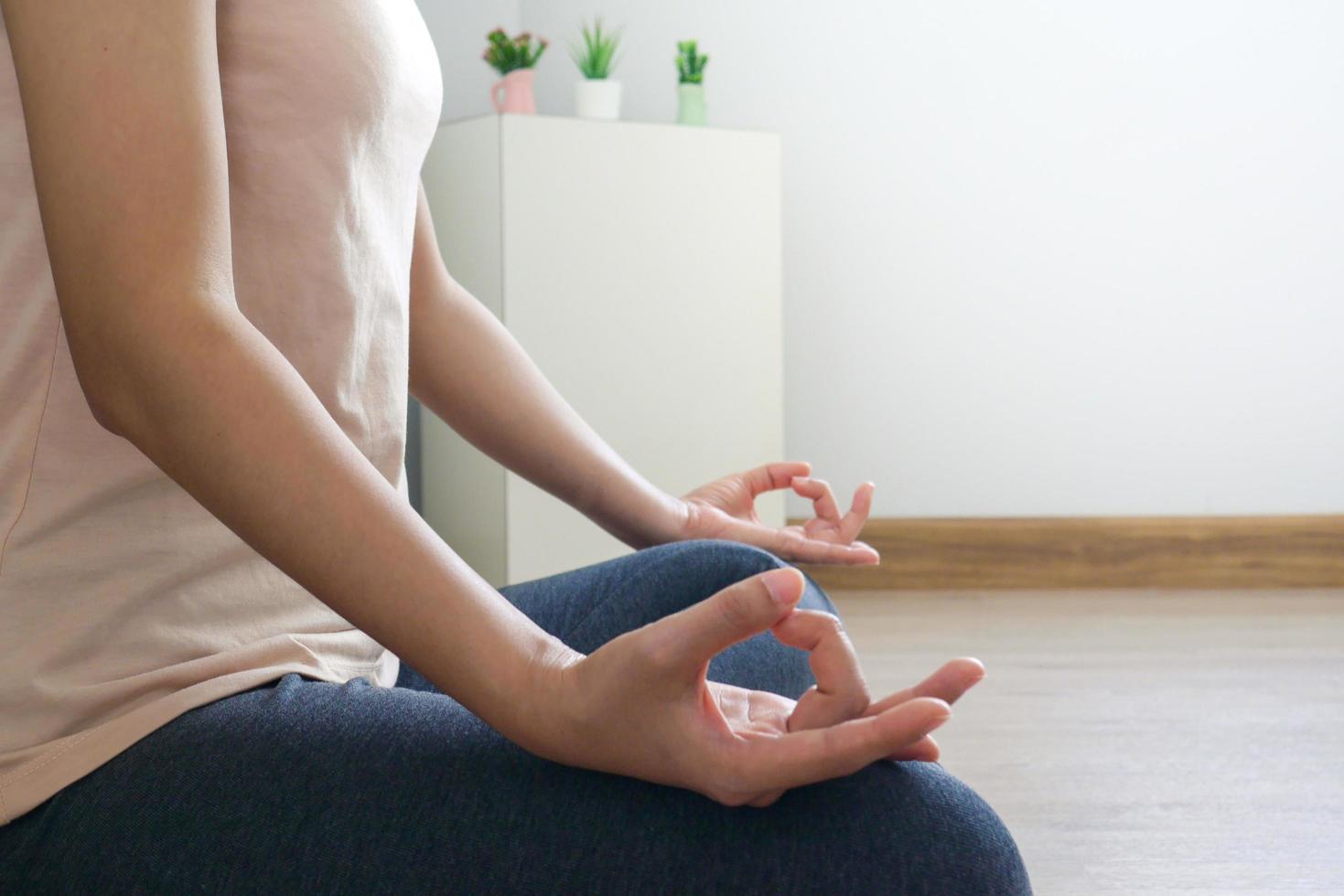 fechar acima do mão mulher práticas ioga e meditação em a lótus postura dentro de casa. foto