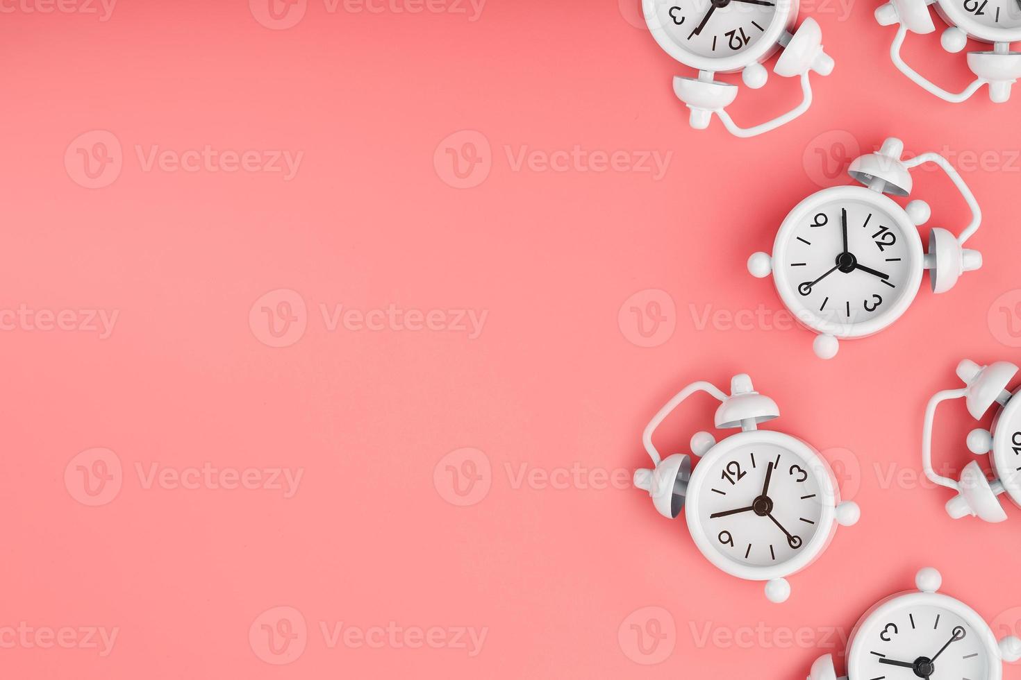 uma padronizar do muitos branco clássico alarme relógios dentro a Formato do uma padronizar em uma Rosa fundo. topo Visão com uma cópia de do a espaço, plano deitar. foto