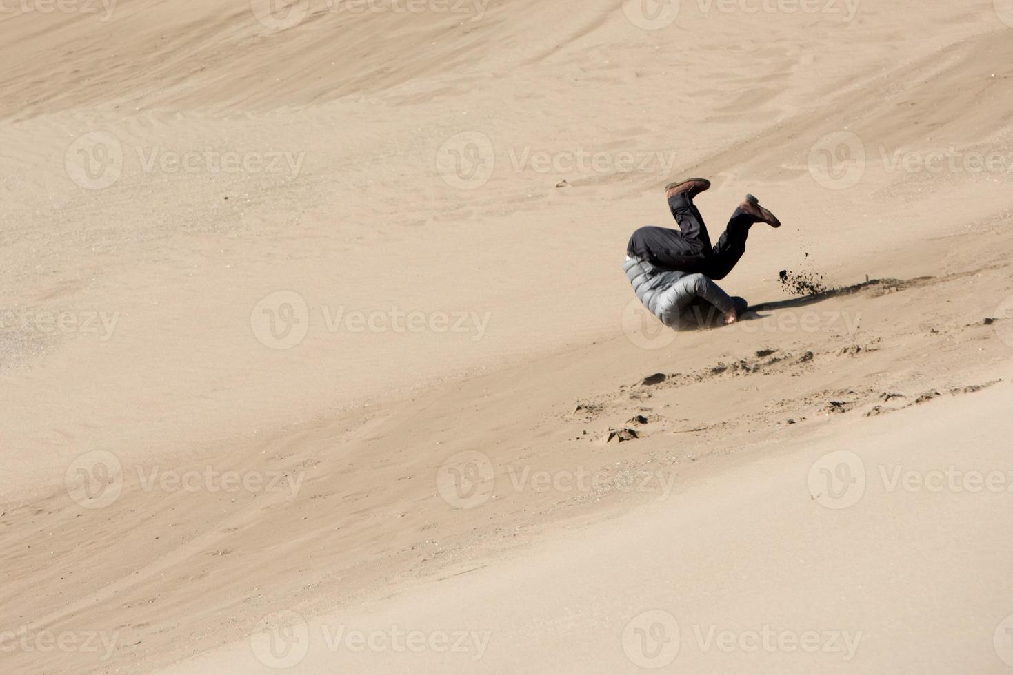 homem rolando em areia dunas foto