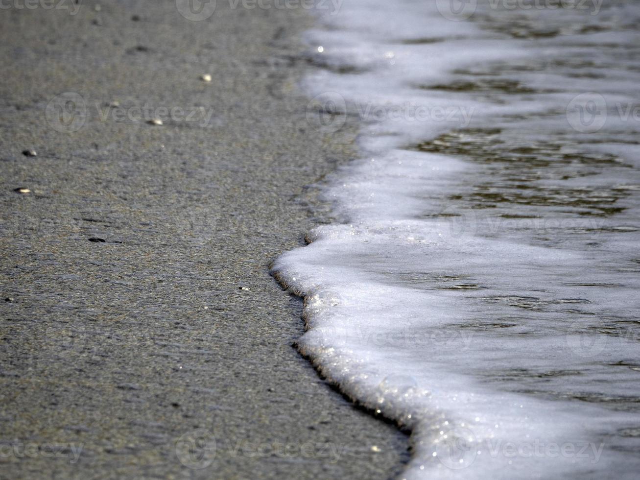 espuma de ondas do mar na praia de areia foto