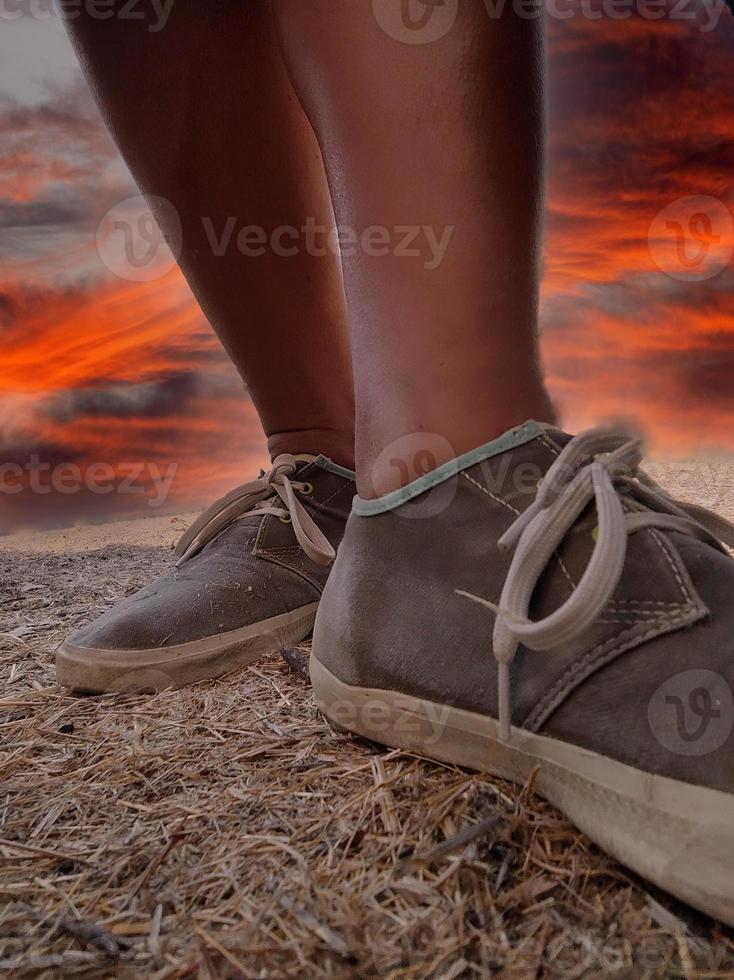 jovem cara sapatos detalhe em pôr do sol fundo ao ar livre foto