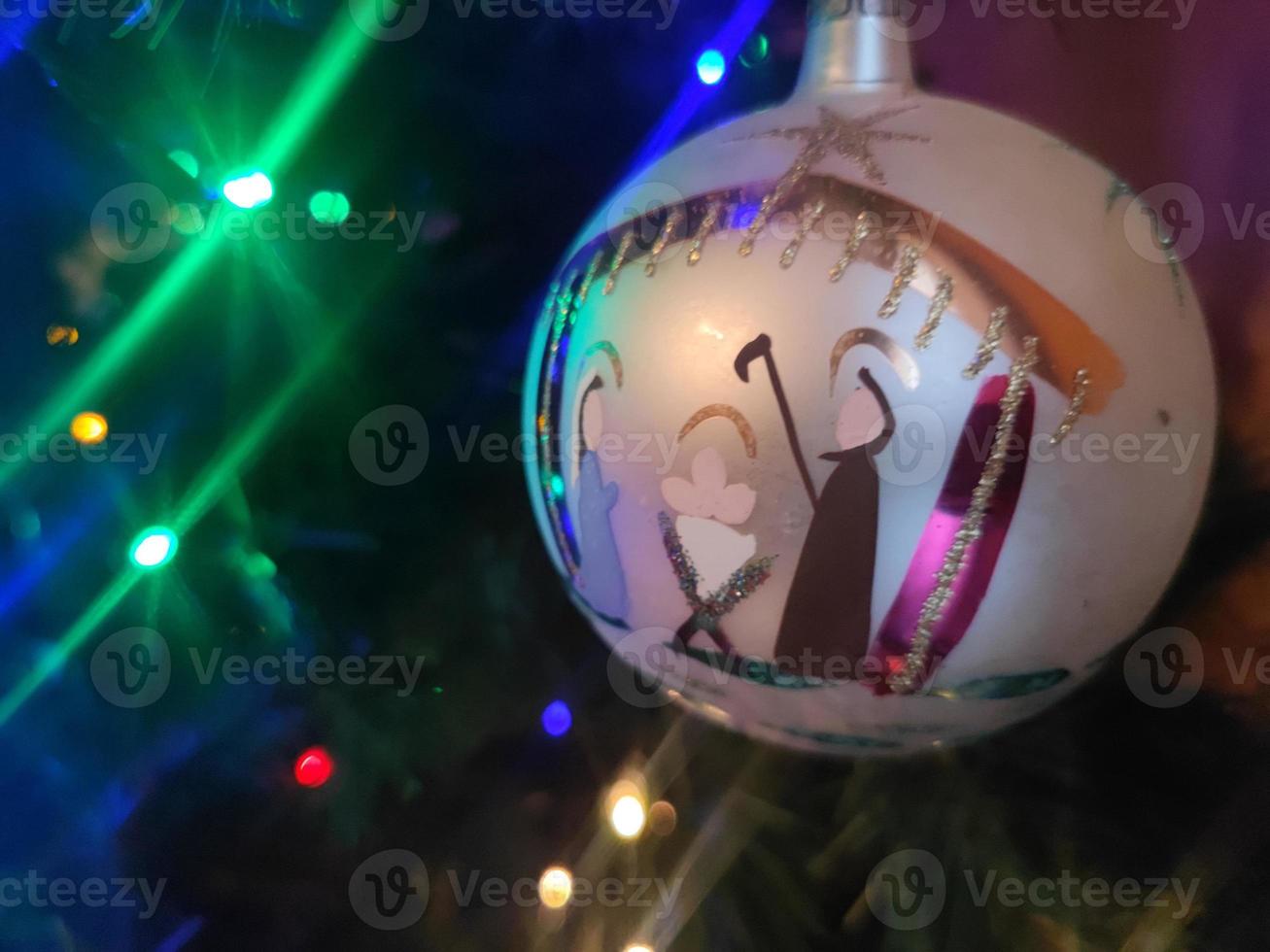 bola de natal de vidro feita à mão no detalhe da árvore de natal luzes desfocadas foto