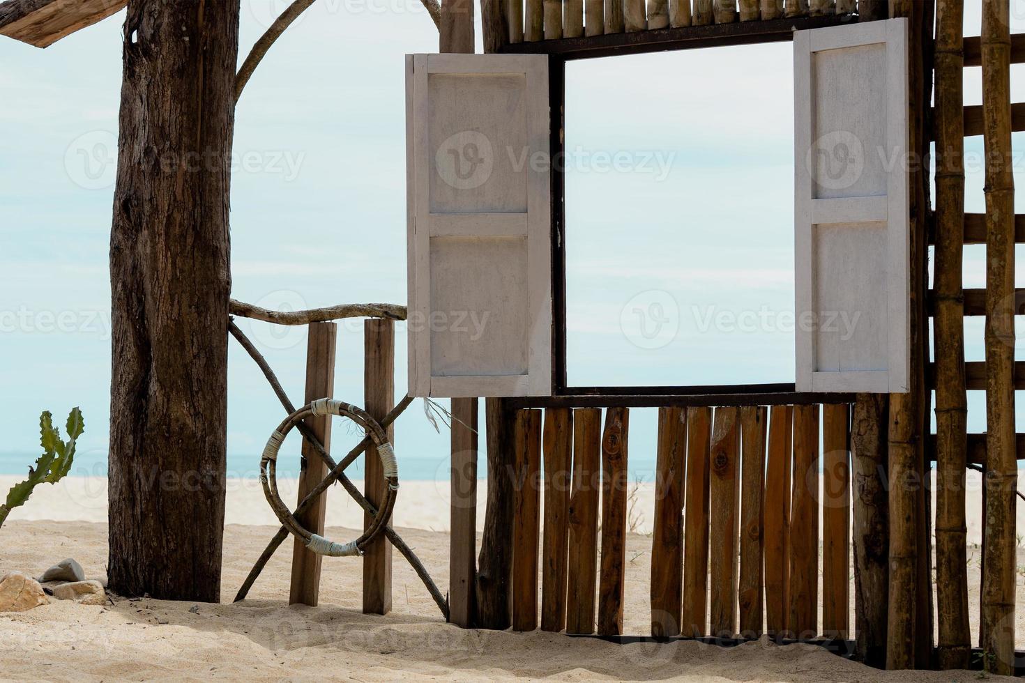 de madeira janela quadro, Armação de a sae dentro ensolarado dia verão, de praia cabana em areia de praia com janela aberto através mar visualizar, beira-mar Visão ponto para verão feriado promover ou produtos apresentação foto