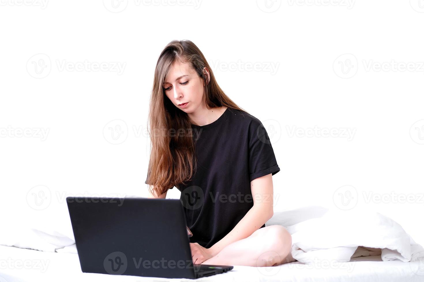 jovem mulher trabalhando em computador portátil às lar. trabalhos on-line. cama descansar. trabalhador autonomo menina funciona. foto