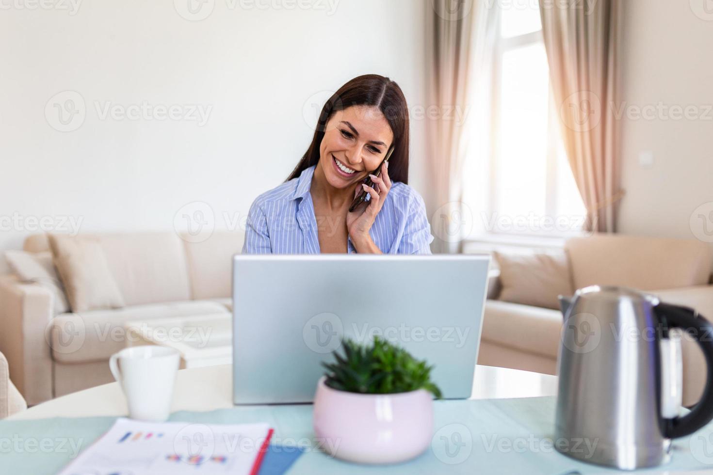 sorridente fêmea multitarefa trabalhando em computador dentro escritório falando sobre telefone, feliz mulher trabalhador usando computador portátil, rindo Falando com amigo em célula ou comunicando com cliente on-line, trabalhos a partir de casa foto