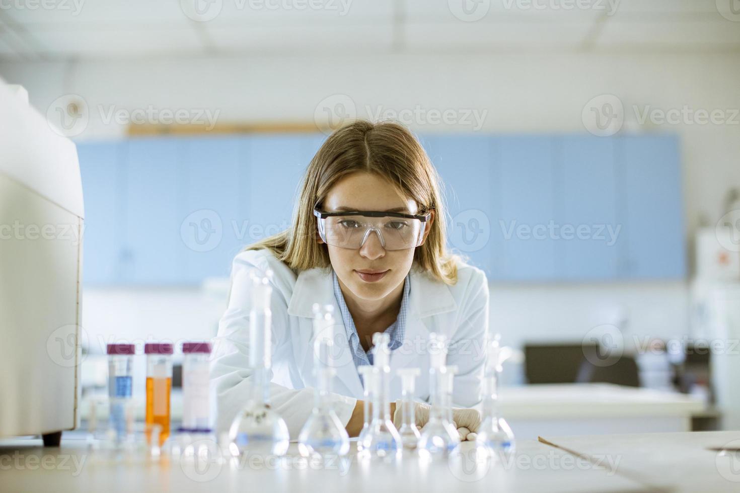 pesquisadora médica ou científica olhando para frascos com soluções em um laboratório foto