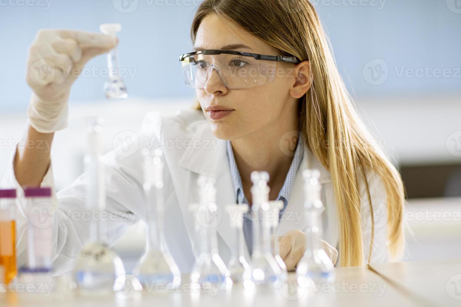 pesquisadora médica ou científica olhando para frascos com soluções em um laboratório foto