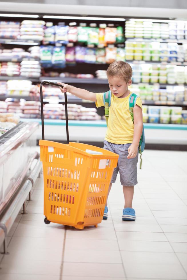 menino com um carrinho de compras na loja foto