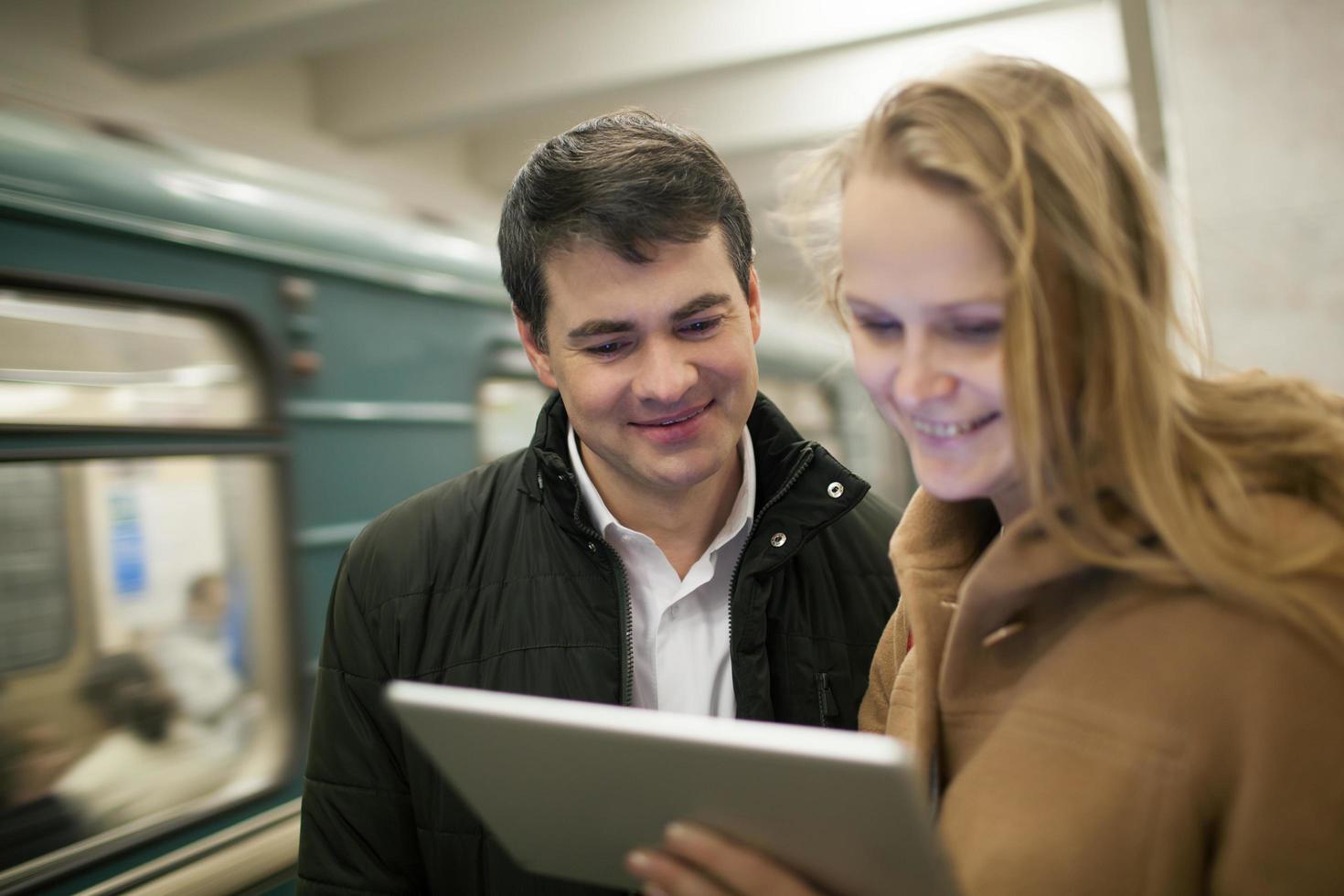 casal usando um tablet na estação de metrô foto