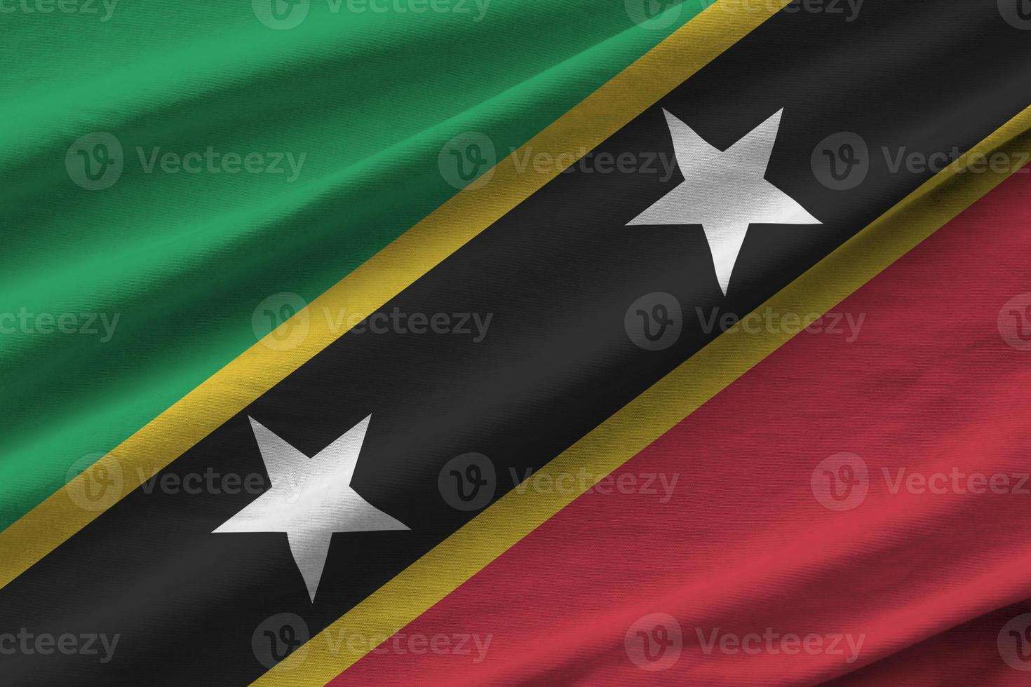 bandeira de São Cristóvão e Nevis com grandes dobras acenando de perto sob a luz do estúdio dentro de casa. os símbolos oficiais e cores no banner foto