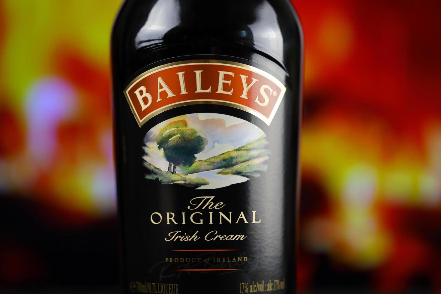 kyiv, ucrânia - 4 de maio de 2022 garrafa de álcool original de baileys na mesa de madeira com lareira vermelha foto