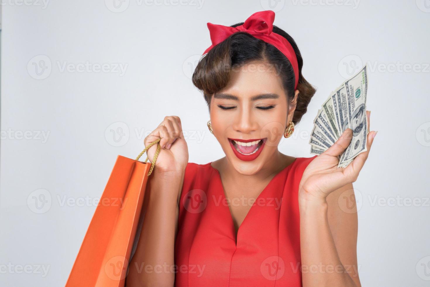 linda mulher asiática segurando sacolas coloridas e dinheiro foto