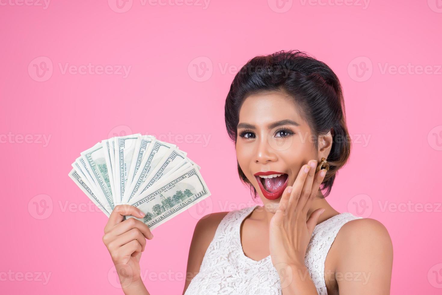 mulher bonita feliz segurando dólares foto