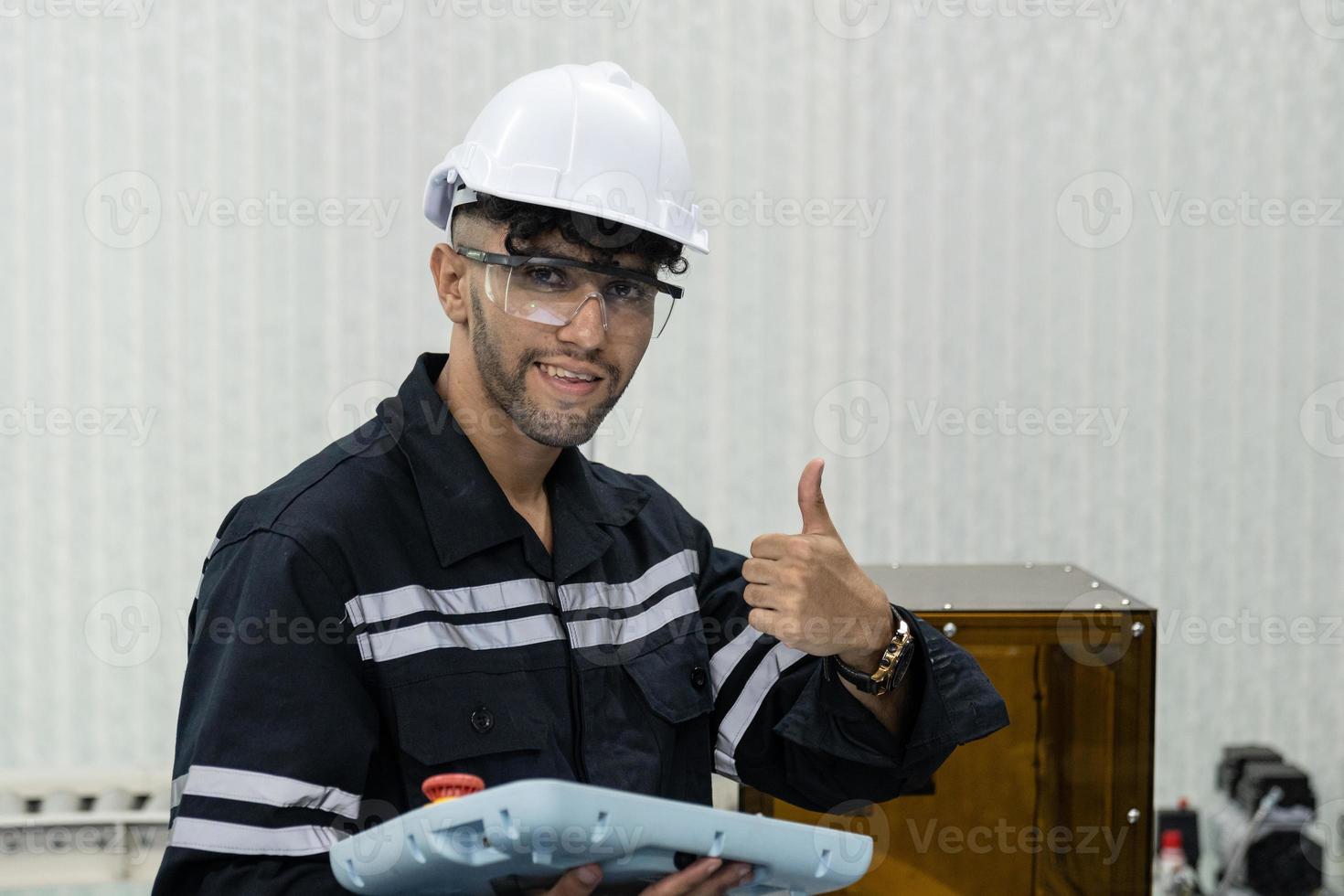 retrato do a indiano masculino engenheiro com capacete e segurança óculos mostrando polegares acima foto