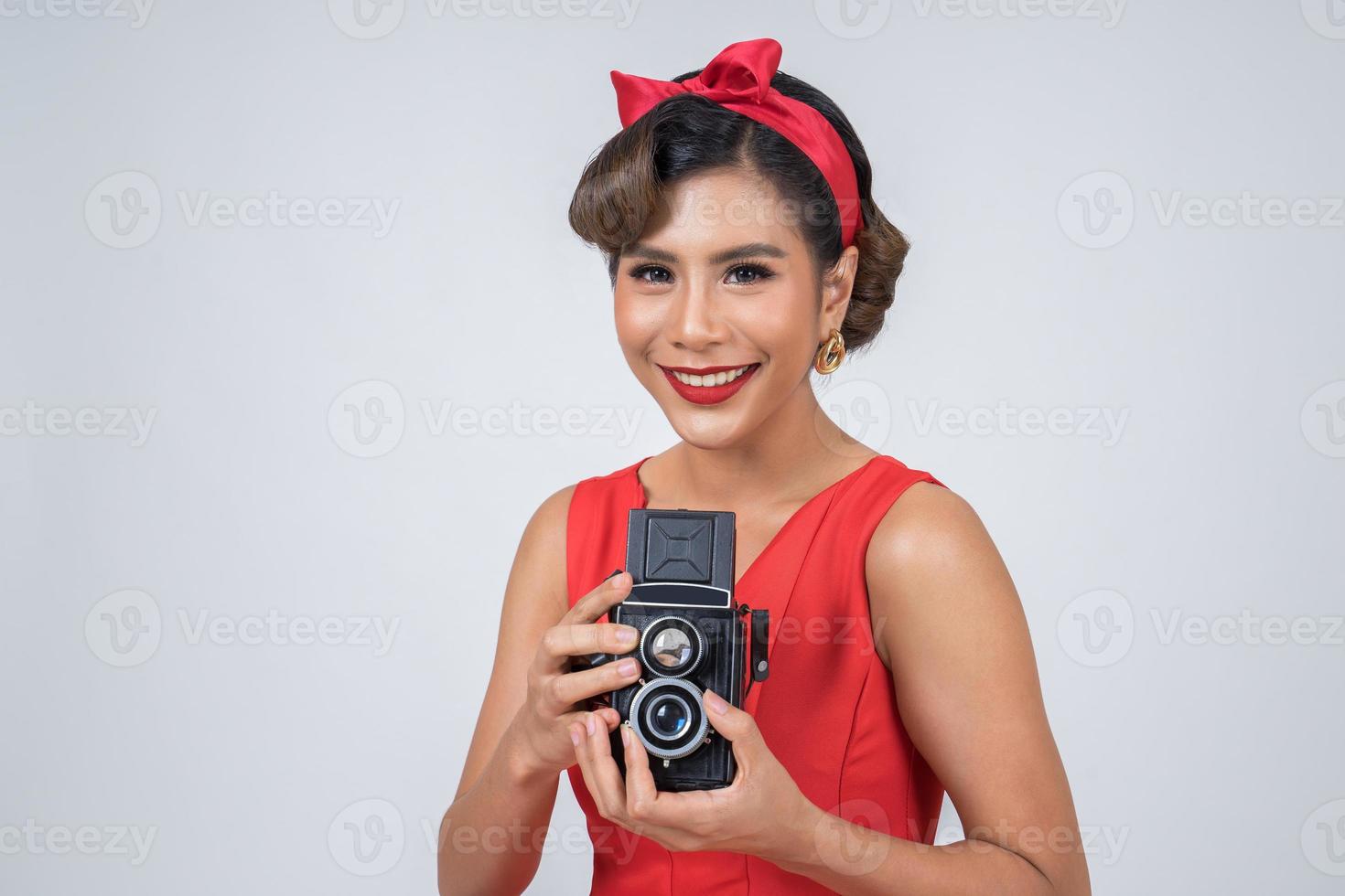 Fotógrafa feliz e elegante segurando uma câmera retro vintage foto