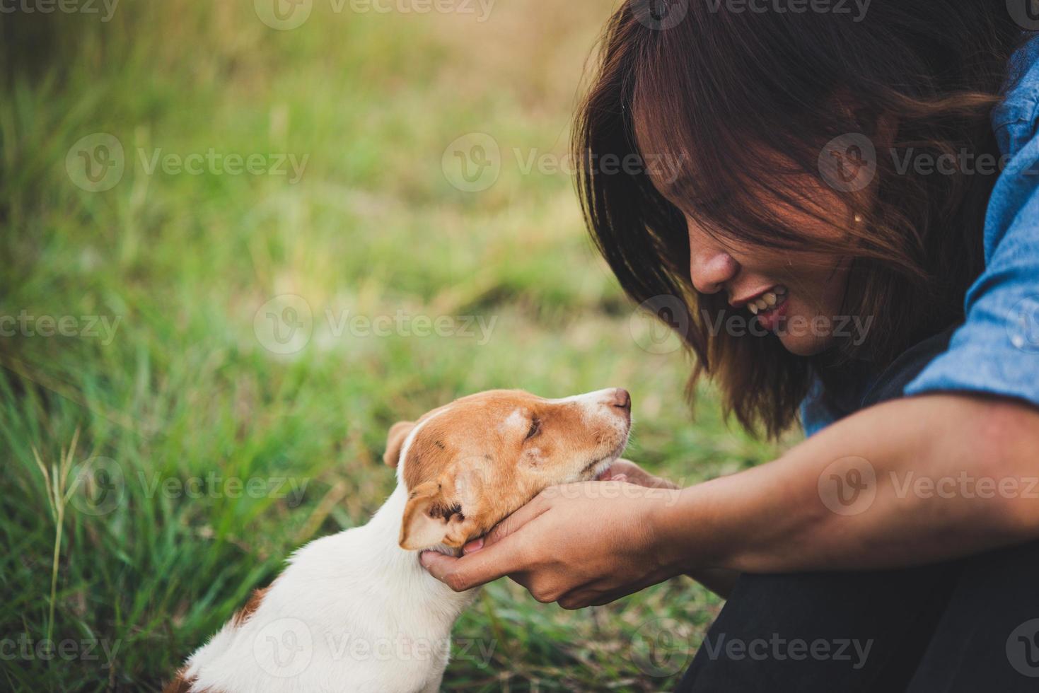 garota feliz alegre hipster brincando com seu cachorro no parque durante o pôr do sol foto