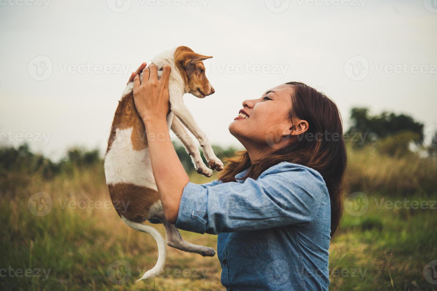 garota feliz alegre hipster brincando com seu cachorro no parque durante o pôr do sol foto