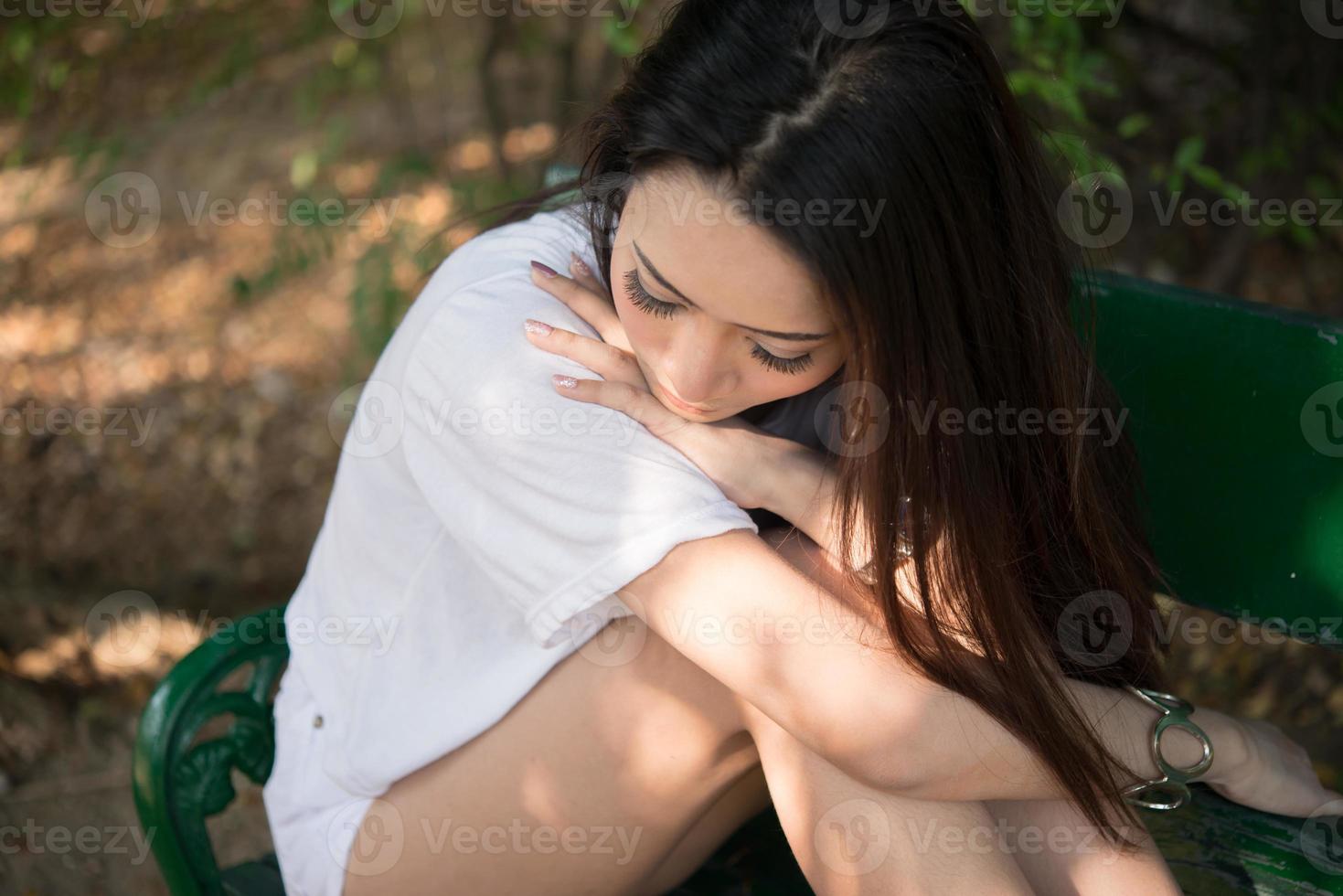 mulher triste e solitária sentada em um banco sozinha no parque foto