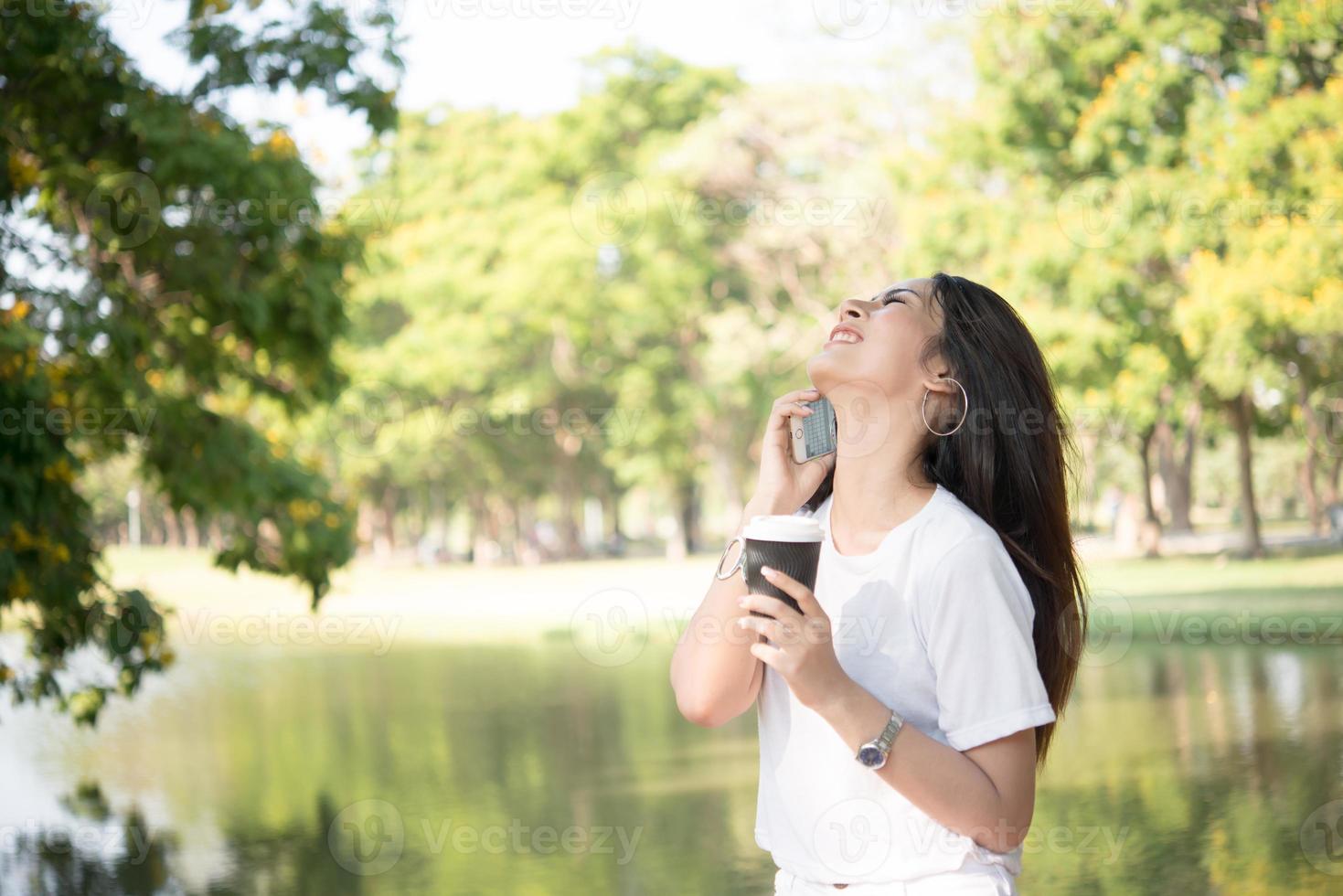 bela jovem segurando uma xícara de café descartável enquanto fala ao telefone foto