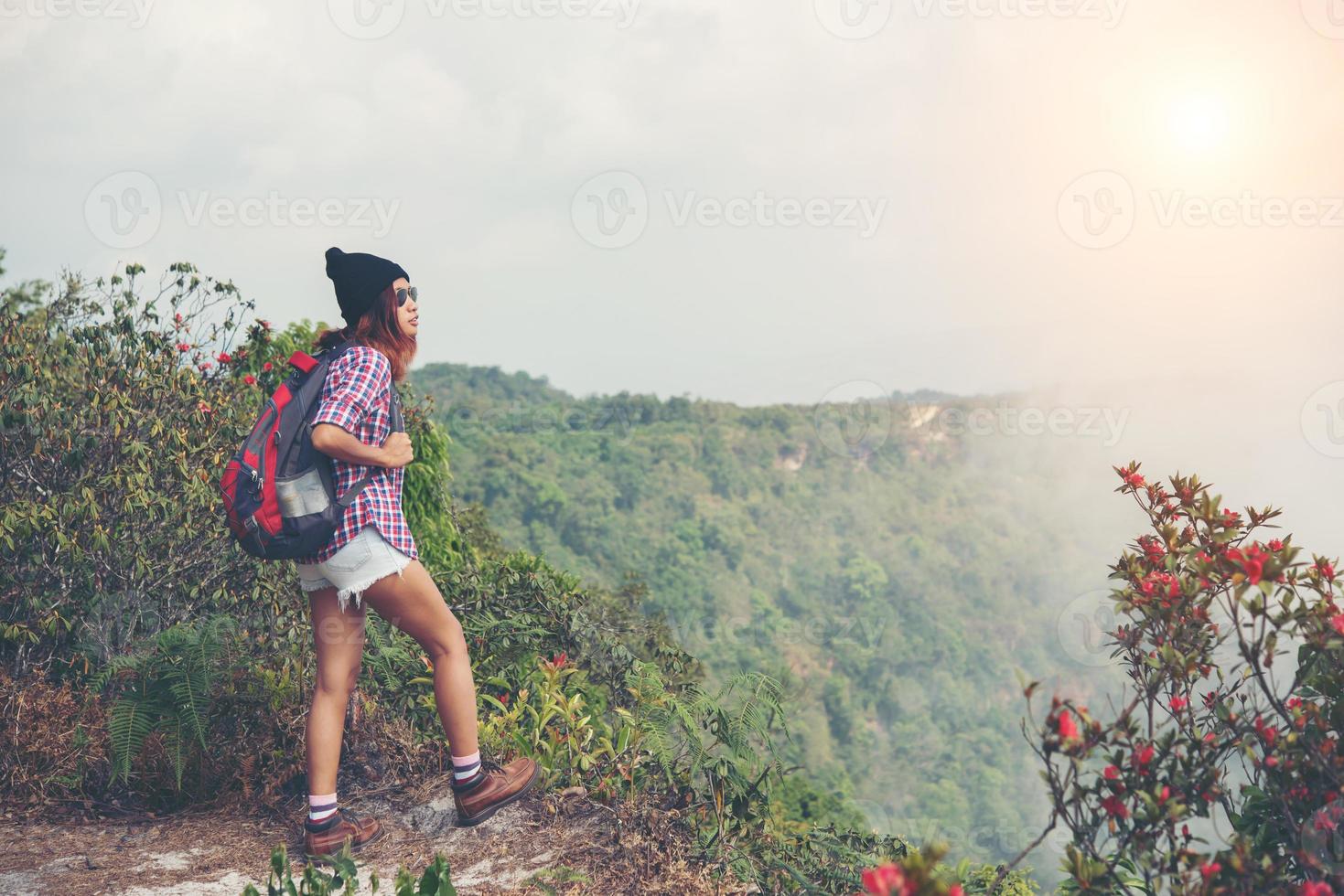 caminhante com mochila no topo de uma montanha apreciando a vista da natureza foto