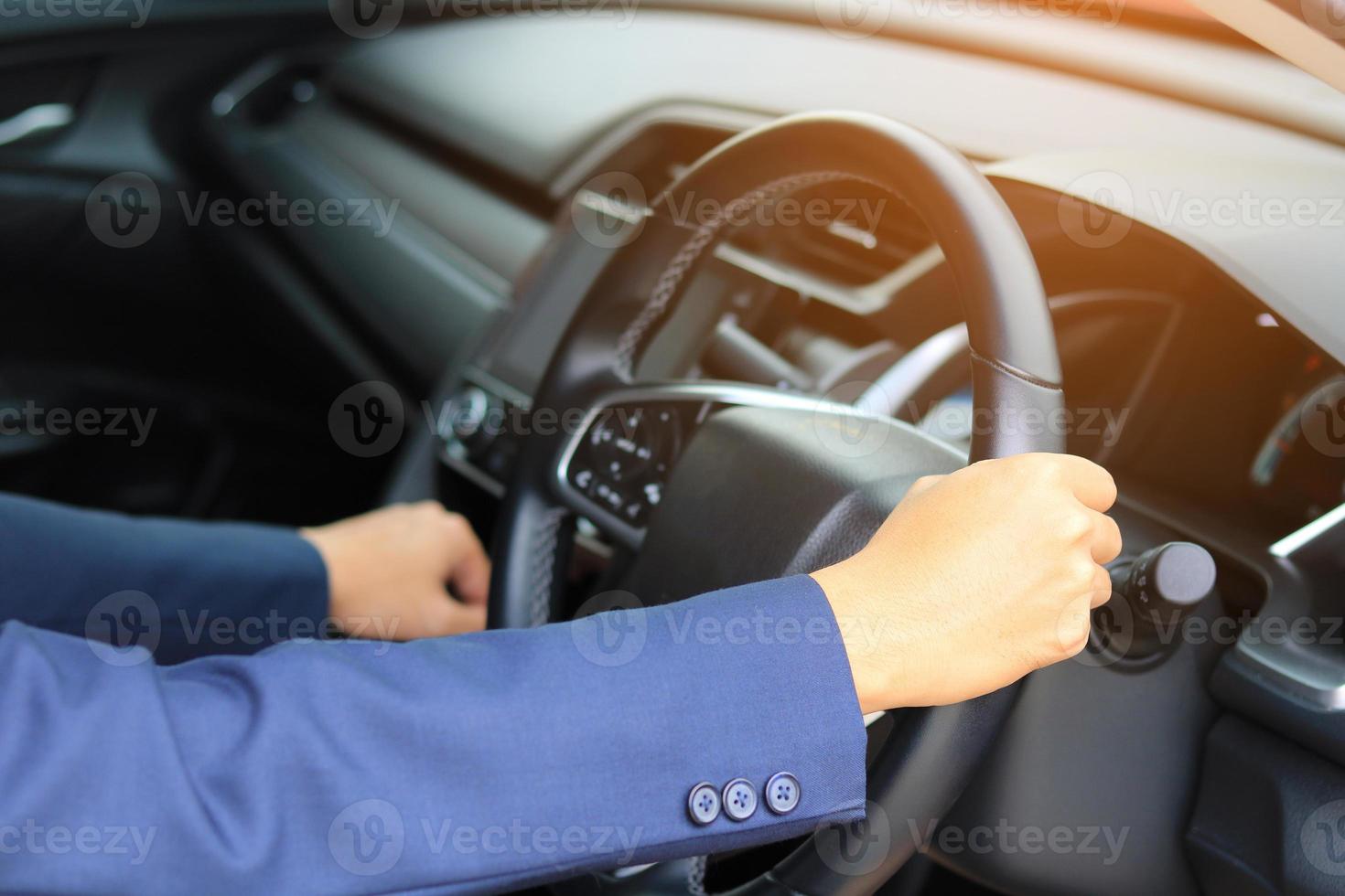 mãos segurando o volante no interior do carro foto