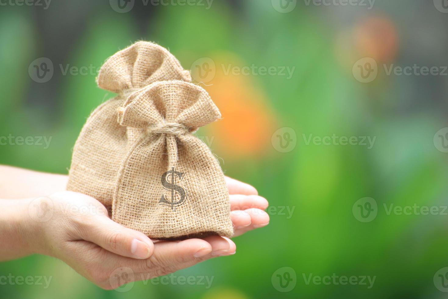 mãos segurando dois sacos de aniagem com o símbolo do dólar foto