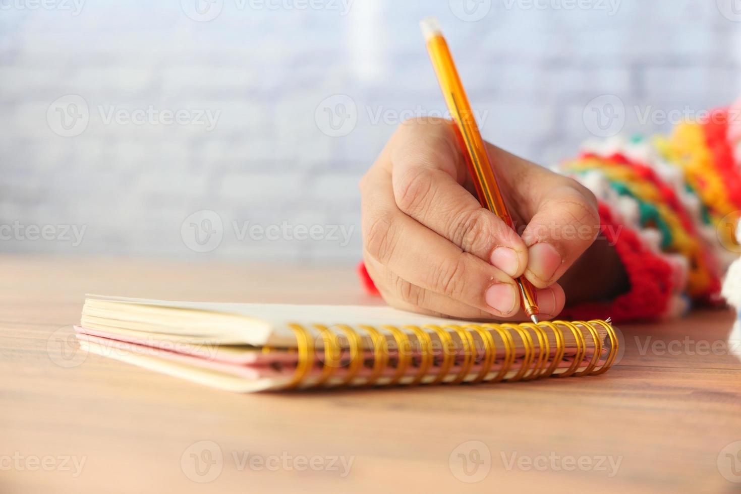 close-up de uma mulher escrevendo à mão no bloco de notas foto