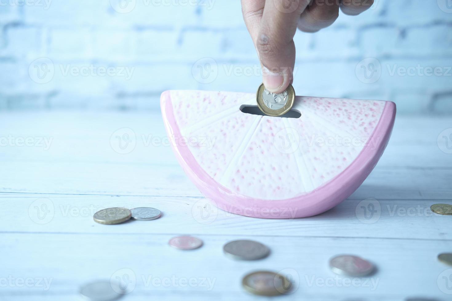 mão de uma pessoa guardando moedas em um banco de moedas foto