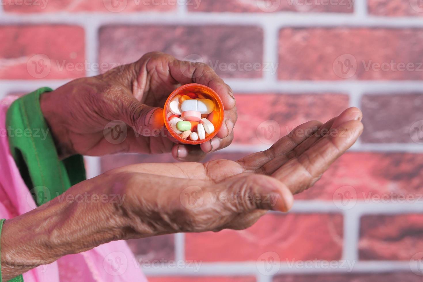 close-up de comprimidos e cápsulas na mão de uma mulher idosa foto