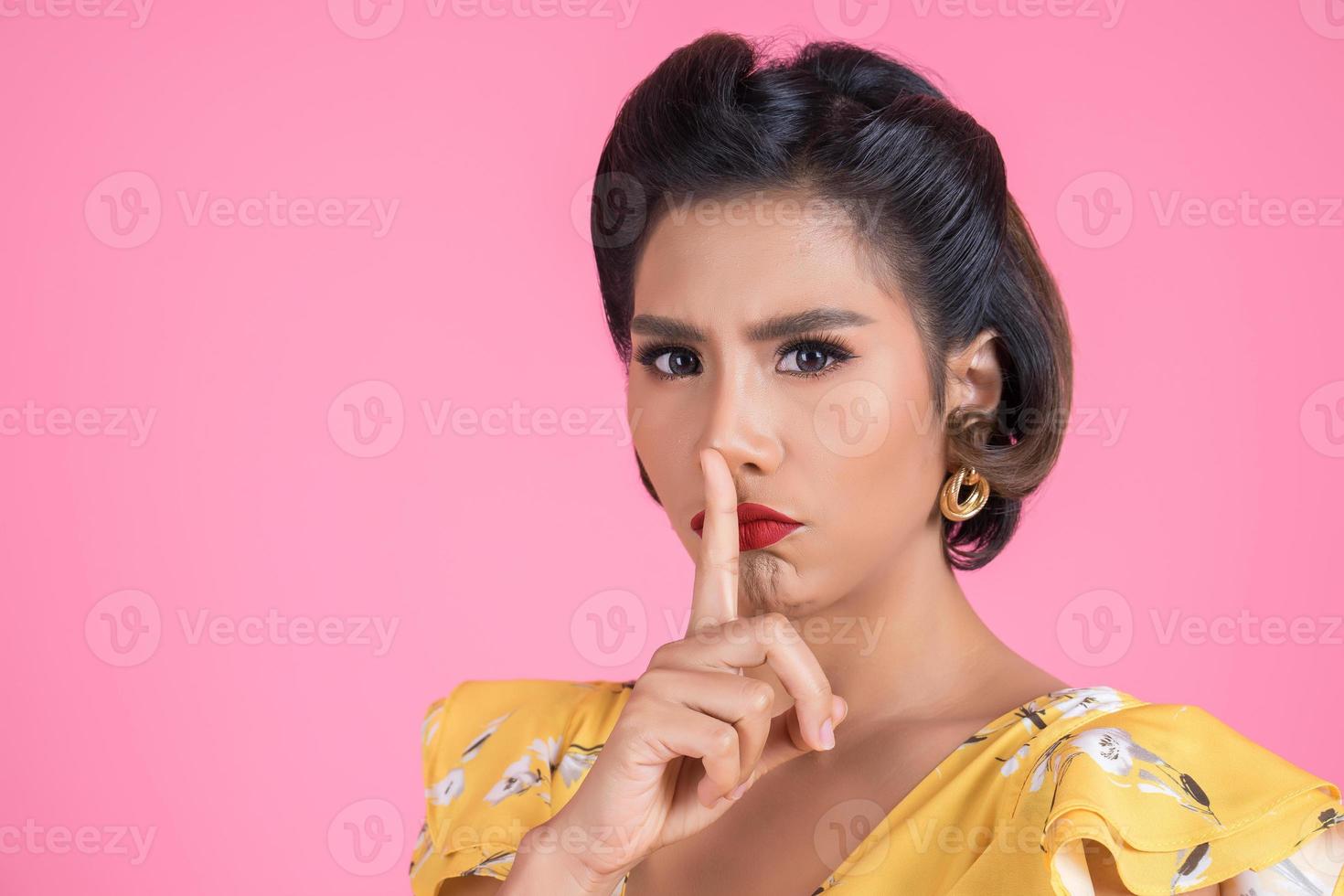 Mulher asiática com lábios vermelhos e dedo mostrando silêncio silencioso foto