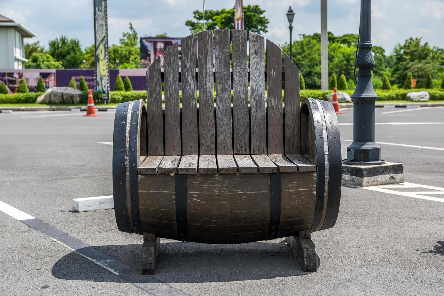 cadeira de madeira feita de um barril em um estacionamento foto