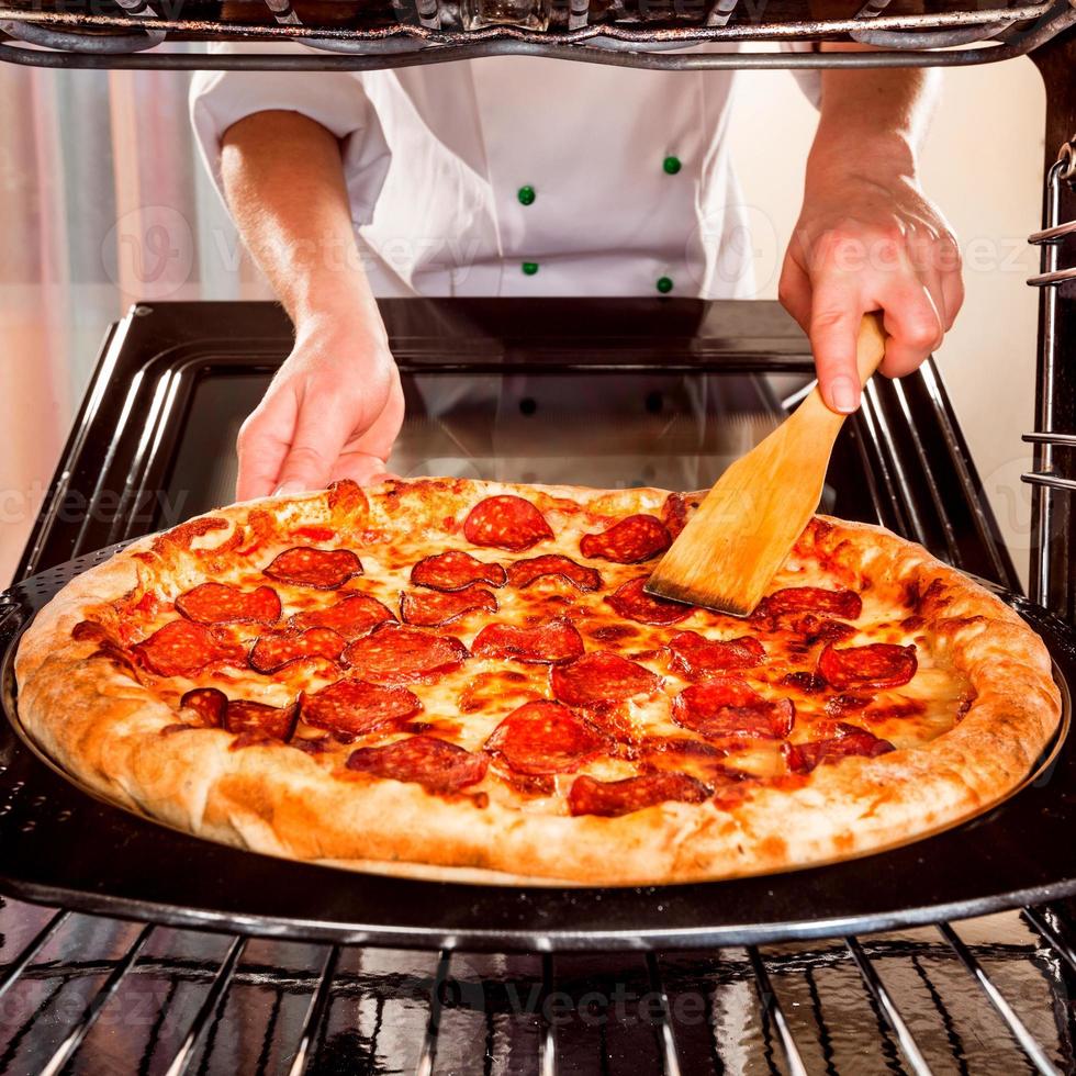 clássico pizza homem com mão queijo em a mesa dentro uma cafeteria em uma de madeira ficar de pé com uma cortar triangular peça e uma pizza faca foto