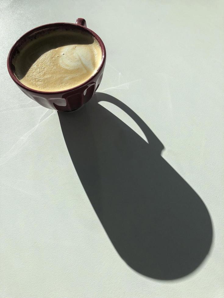 café com leite com sombra longa em uma mesa branca foto
