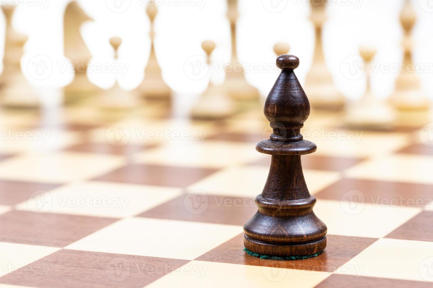 Preto bispo contra branco xadrez peças em borda foto