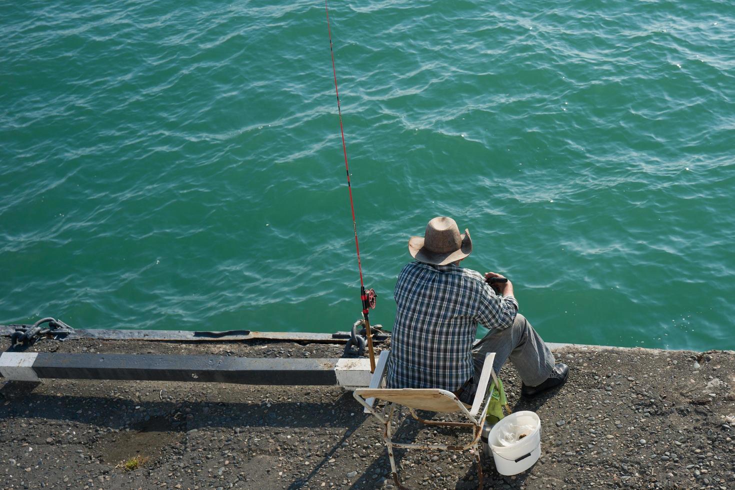 homem sentado pescando em um píer foto