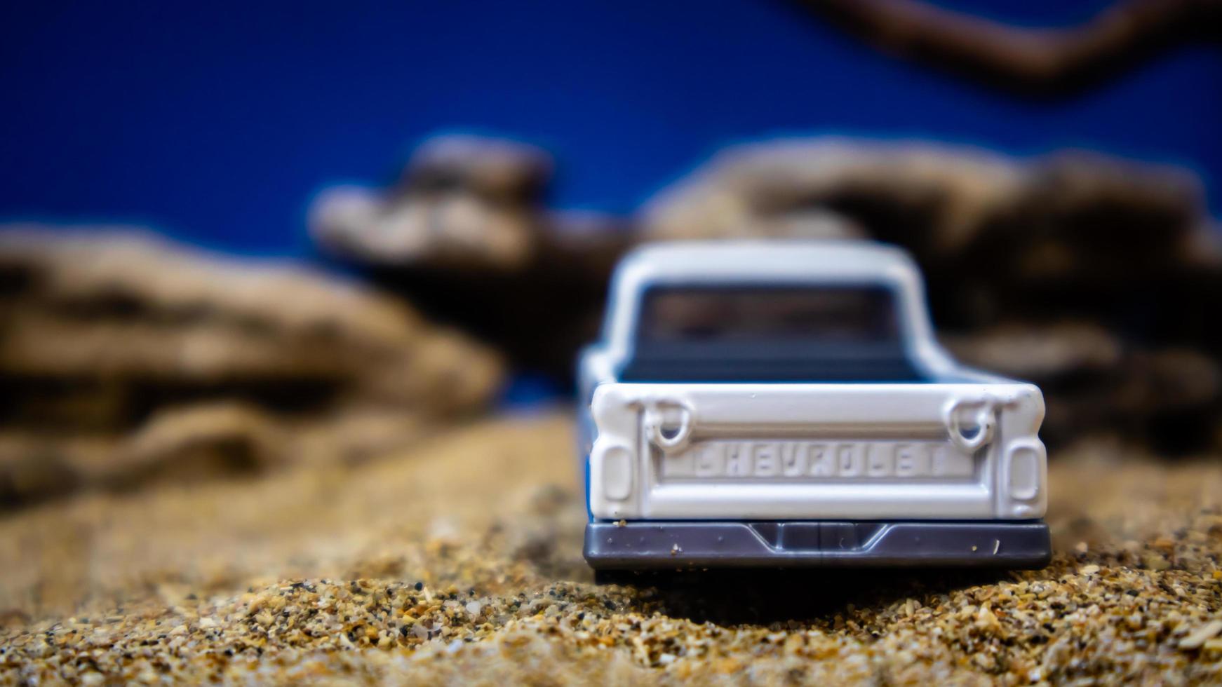 minahasa, indonésia janeiro de 2023, um carro de brinquedo na areia com um fundo de pedras e céu azul foto