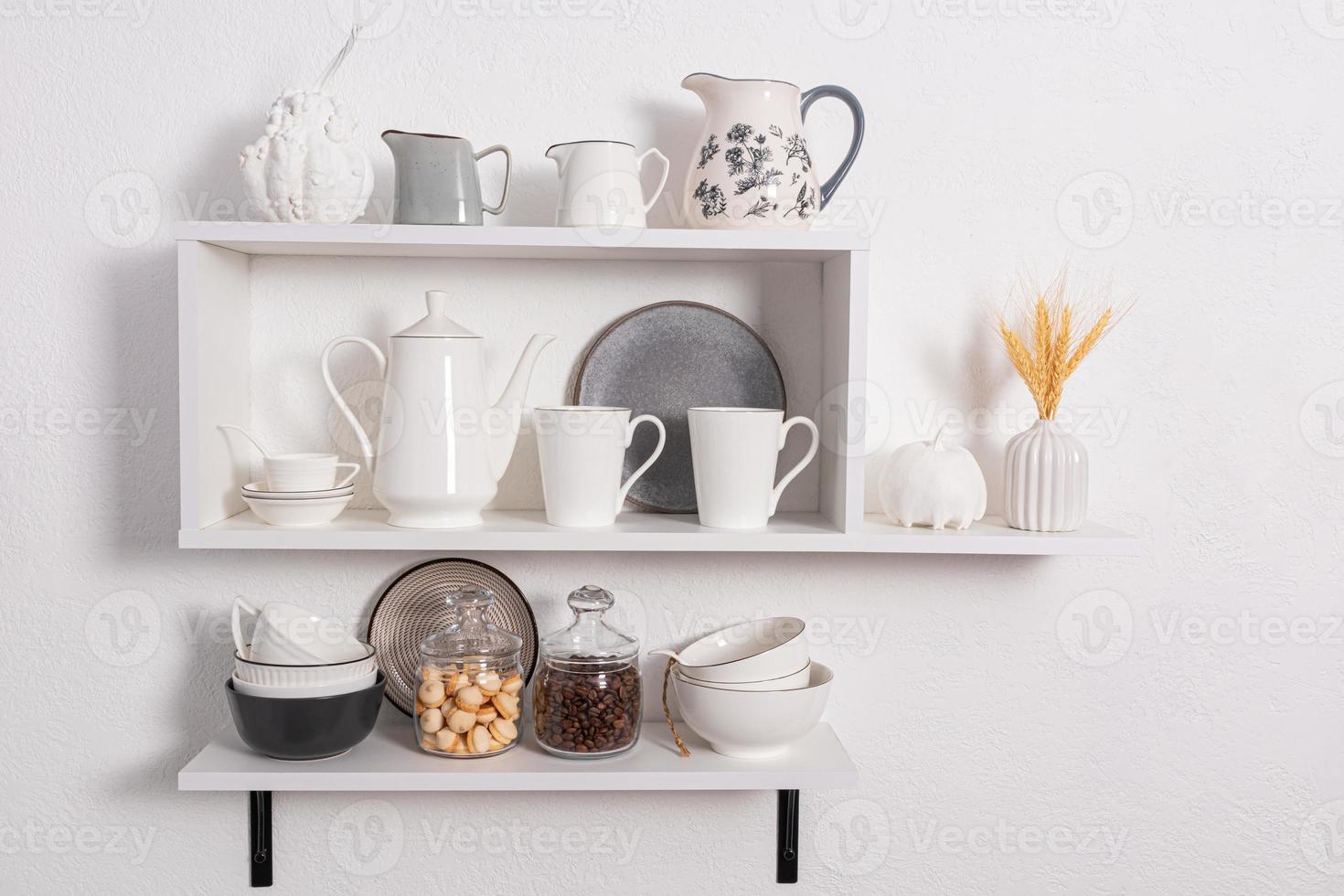 lindas prateleiras brancas com utensílios de cozinha em uma parede texturizada branca. interior da cozinha em tons de branco. vista frontal. cozinha ecologicamente limpa. foto